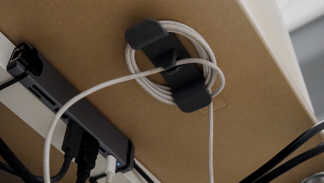 Under-desk cable management tray holding power strips and neatly organized cords beneath a wooden desk.