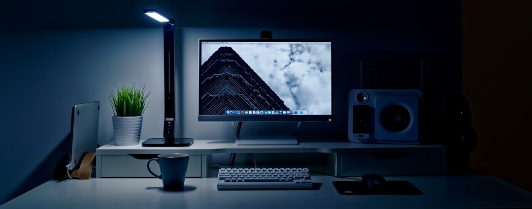 A sleek LED monitor light bar mounted on top of a computer display illuminating a clean home office desk surface.