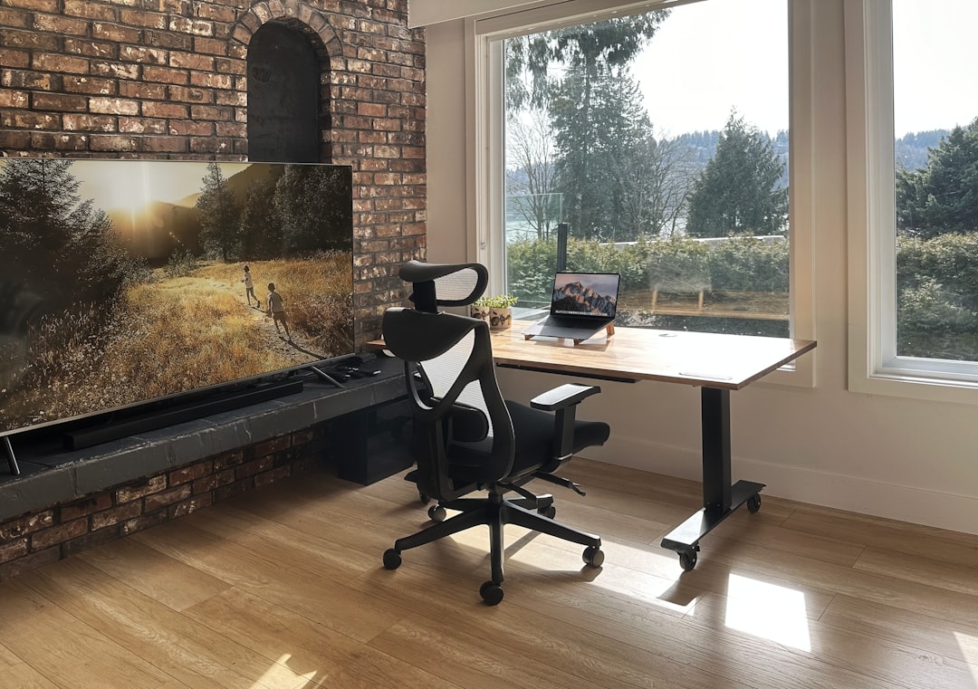 Clean, well-lit home office with an L-shaped desk featuring computer monitors on one wing and an open notepad writing area on the other wing
