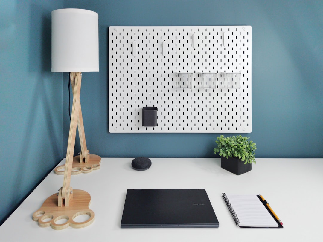 Pegboard storage system with office accessories mounted above a small desk.