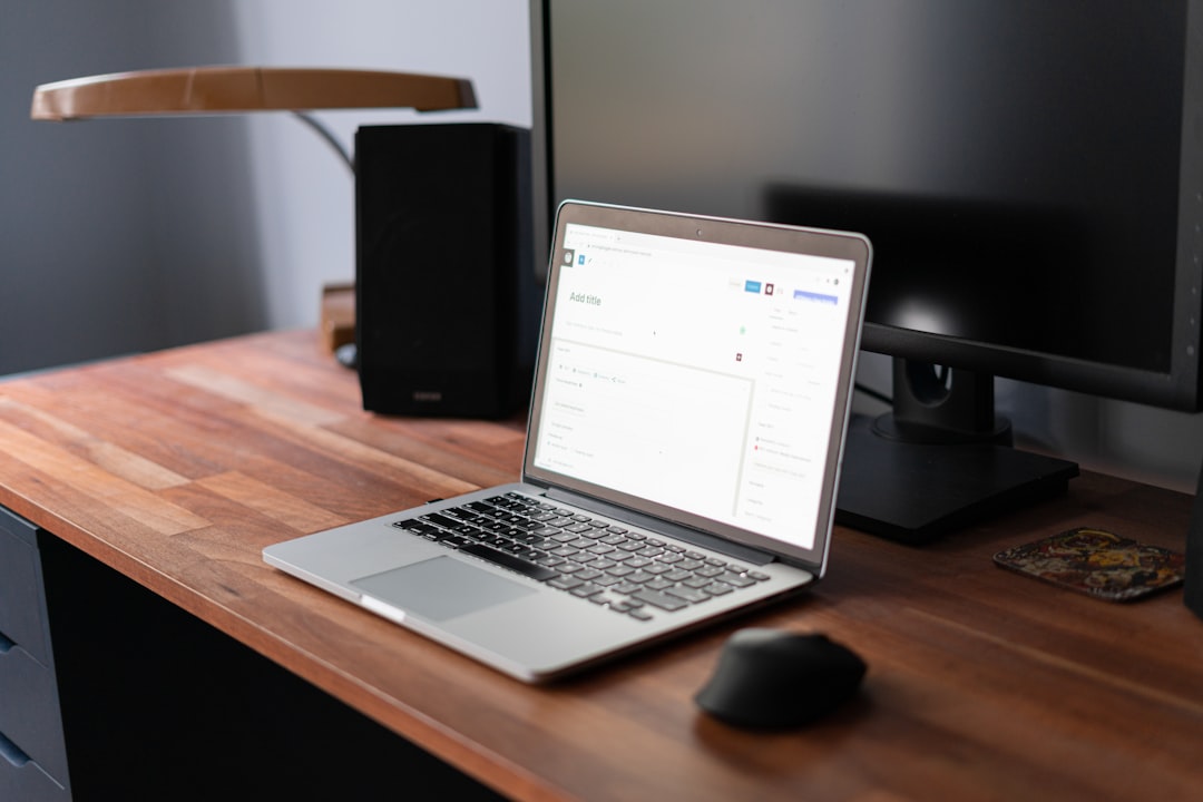 Digital air quality and CO2 monitor sitting on a modern wooden office desk near a laptop setup