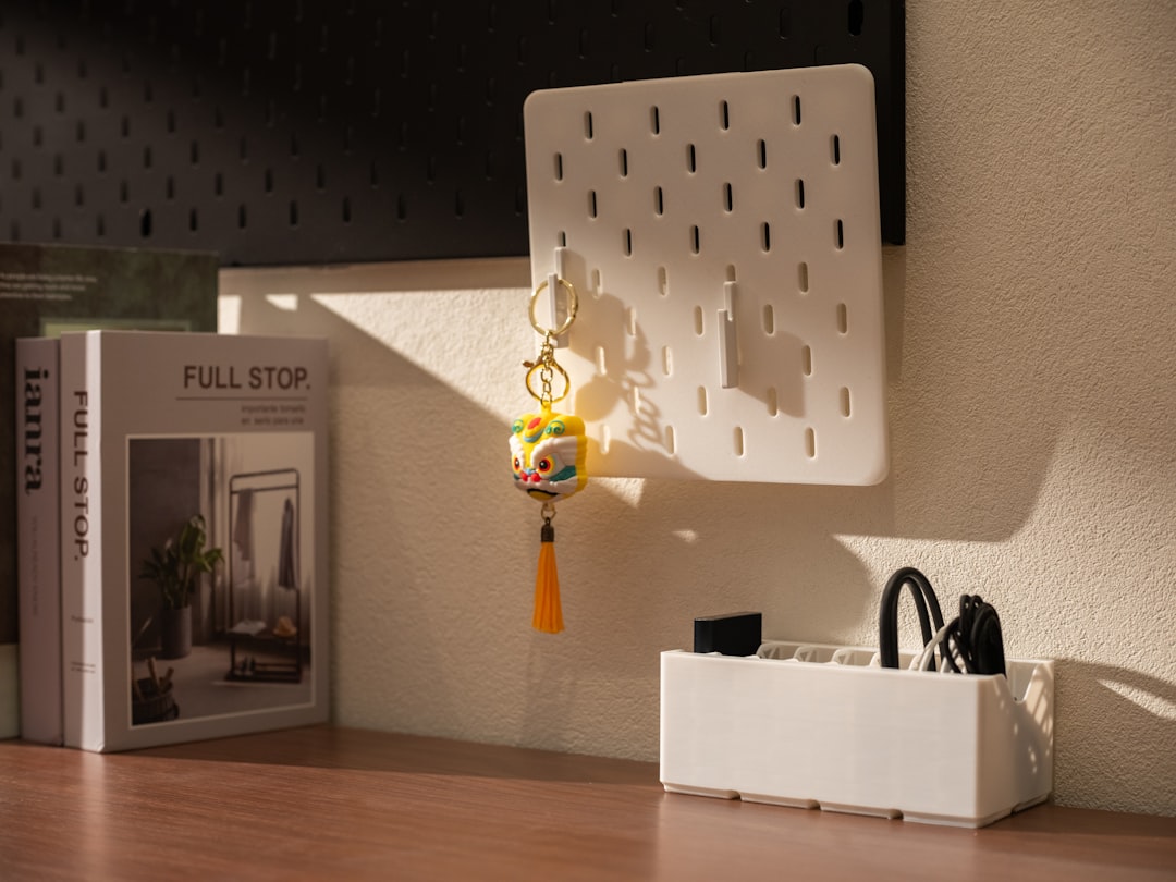 A clean white clamp-on desk pegboard holding headphones and stationery on a small home office desk.